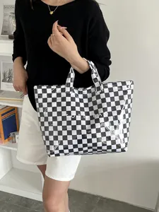 Detail of glossy checkerboard tote bag with TOTE BAG text print shown in lifestyle setting