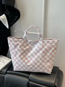 Detailed view of pink checkered tote bag with white TOTE BAG text on a stylish backdrop