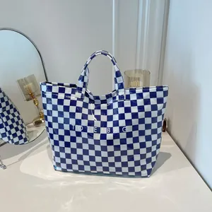 Blue and white checkered transparent tote bag with TOTE BAG print in a modern setting