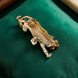 Golden tiger brooch in roaring pose with secure back pin on dark green velvet