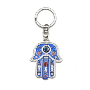 Hamsa Hand Evil Eye keychain with blue enamel and Hebrew symbols on white background