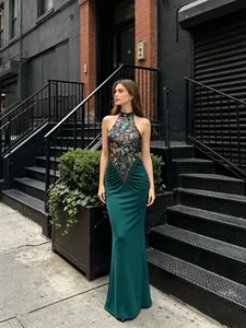 Deep green halter evening gown with floral embroidery, sequins, and a fishtail hemline