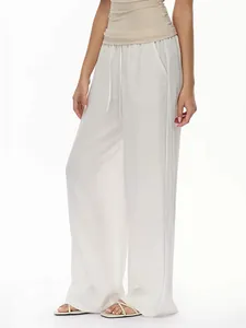 Detail of high-waist white wide-leg trousers featuring elastic waistband and drawstring