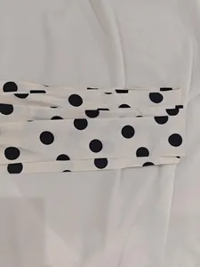 Close-up of off-white retro polka dot fabric with elegant waist belt folds