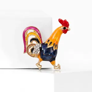 Détail de broche coq colorée avec crête rouge, corps bleu et ailes en strass