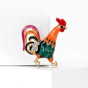 Détail d'une broche coq en émail coloré avec strass brillants sur base dorée