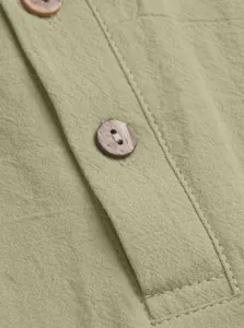 Detail of light green linen fabric texture with a premium dark wood-grain button