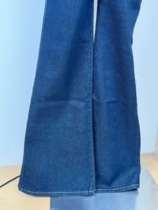 Detailed close-up of dark blue denim flared jeans with classic contrast stitching