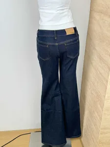 Detail of dark blue flared jeans featuring classic back pockets and brown leather waist patch