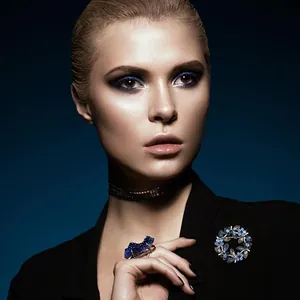 Close-up of deep blue crystal flower brooch and gemstone ring on fashion model