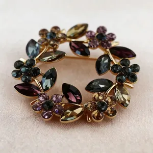 Elegant floral crystal wreath brooch with multicolored stones on pink silk fabric