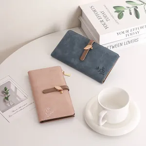 Detail von rosa und blauen langen Brieftaschen mit Blattanhänger und floraler Stickerei auf Leder