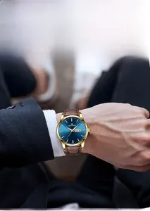 Detail einer Golduhr mit blauem Zifferblatt und braunem Lederband zu einem Business-Anzug