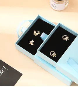 Detail of blue jewelry box featuring drawer design with pearl flower and butterfly earrings