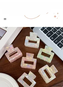 Detailed close-up of iridescent square hair claws in macaron colors on a wood surface