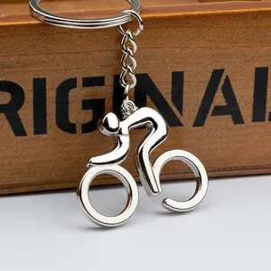 Polished silver metal bicycle keychain with cyclist silhouette against a wood background