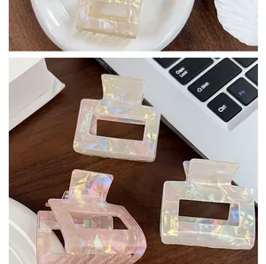 Detailed view of iridescent mermaid-tone square hair claw clips on a desk