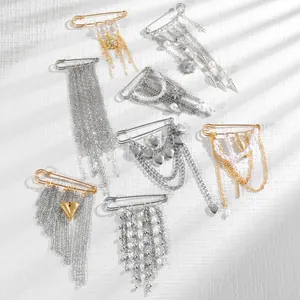 Close-up of vintage punk brooches with metal chains, pearls and heart pendants on white texture