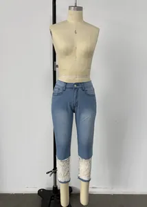 Dettaglio dei jeans capri azzurri con raffinato orlo in pizzo floreale bianco