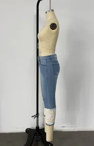 Dettaglio di pantaloni denim blu chiaro con orlo in pizzo floreale su manichino