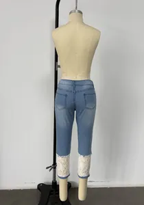 Dettaglio di jeans corti azzurri con raffinato bordo in pizzo floreale bianco sull'orlo