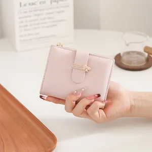 Close-up of pink PU leather folding wallet with gold bow buckle and zipper detail