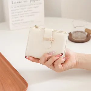 Close-up of off-white PU leather wallet featuring a gold bow buckle and zipper detail