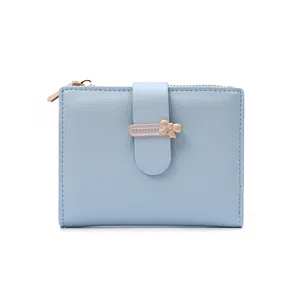 Detail of light blue cross-textured wallet with a gold bow buckle and zip closure
