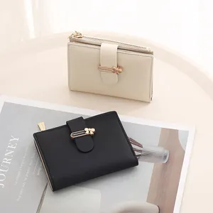Detail view of cream and black short PU wallets with metal bow buckle and zipper