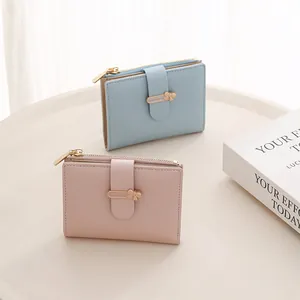 Detail of compact wallets in light blue and pink with metal bow clasp and zip pocket