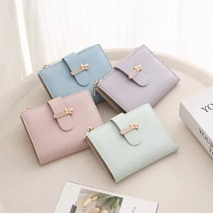 Detail of four pastel PU leather wallets with gold bow buckles and zip closures