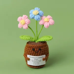 Handgefertigte Häkelblumen im Topf mit rosa und blauen Blumen und kleinem Lächeln