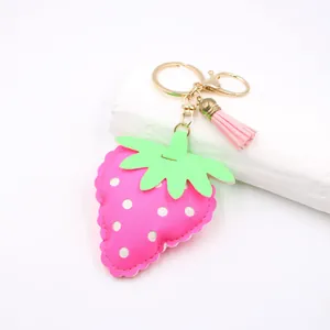 Close-up of pink leather strawberry keychain with white dots and a tassel detail