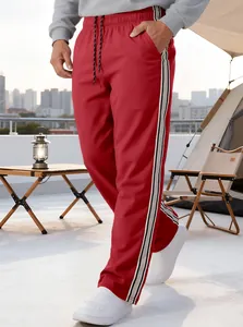 Detail of red sports pants featuring black and white side stripes and adjustable drawstrings