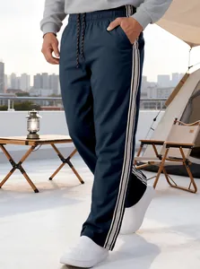 Men's navy athletic pants featuring grey side stripes in an outdoor camping setting