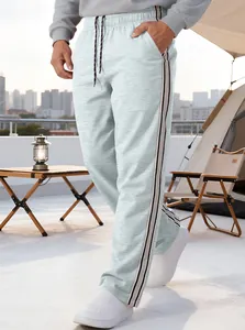 Detail of men's loose sports pants featuring side stripes and drawstring in a camping scene