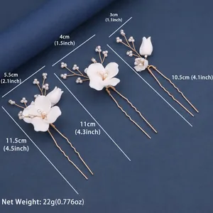 Detailed view of handmade white flower bridal hair pins with pearls and gold U-shaped clips