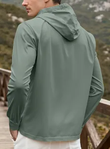 Outdoor view of sage green hooded jacket showing the windproof fabric and side profile