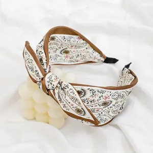 Elegant paisley patterned bow headband in beige fabric with brown border detail