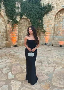 Robe de soirée bustier noire élégante et pochette à paillettes argentée lors d'une fête