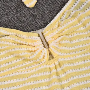 Detailed close-up of yellow and white striped crochet knit top with tie neck detail