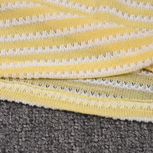 Detail of yellow and white striped knit fabric with decorative scallop lace texture