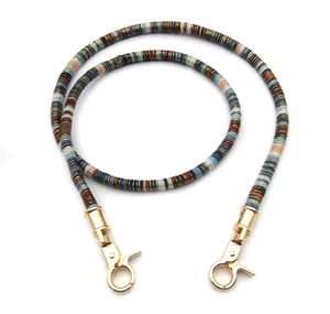 Close-up of colorful woven bohemian bag strap with gold metallic threads and swivel clasps
