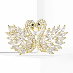 Macro detail of luxury twin swan brooch with gold finish and zircon micro-inlay