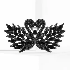 Macro view of twin swan brooch featuring black marquise-cut crystals and zircon inlay