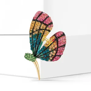 Dettaglio della spilla a farfalla con strass colorati e base dorata su blocchi bianchi