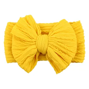 Bright yellow elastic jacquard headband for babies with a large knitted bow detail