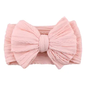Pink jacquard knit baby headband featuring a large elastic textured bow decoration