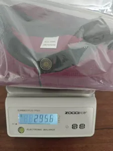 Peso di una camicia bordeaux XXXL su bilancia con indicazione 295,6g e etichetta poliestere