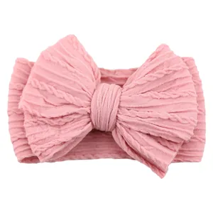 Pink cable knit baby headband featuring a large bow and soft elastic fabric for infants